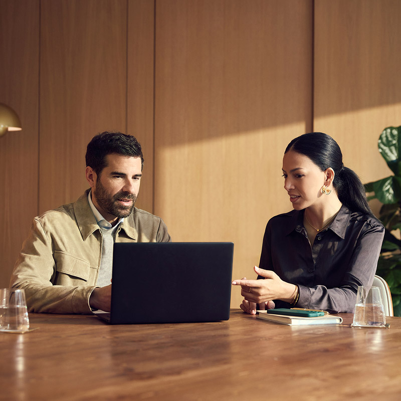 2 people using laptop in office